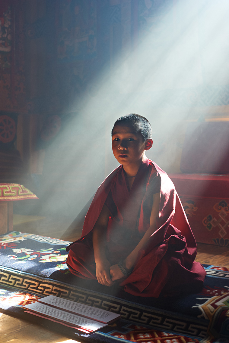 A young monk studies in the prayer room of a Paro Valley monastery, Bhutan. 