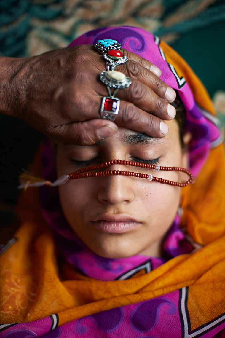 The hands of a healer rest on a sick Muslim girl in Srinagar, Kashmir